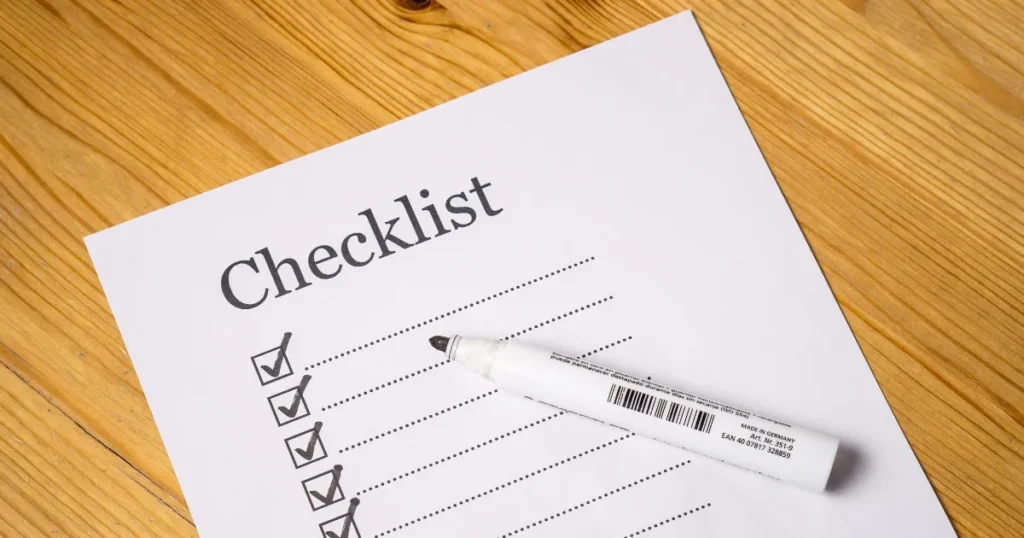木のテーブルに置かれた「Checklist」と書かれた用紙と白いペンの写真